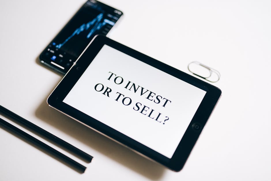 A tablet with text 'To Invest or To Sell?' on a white background